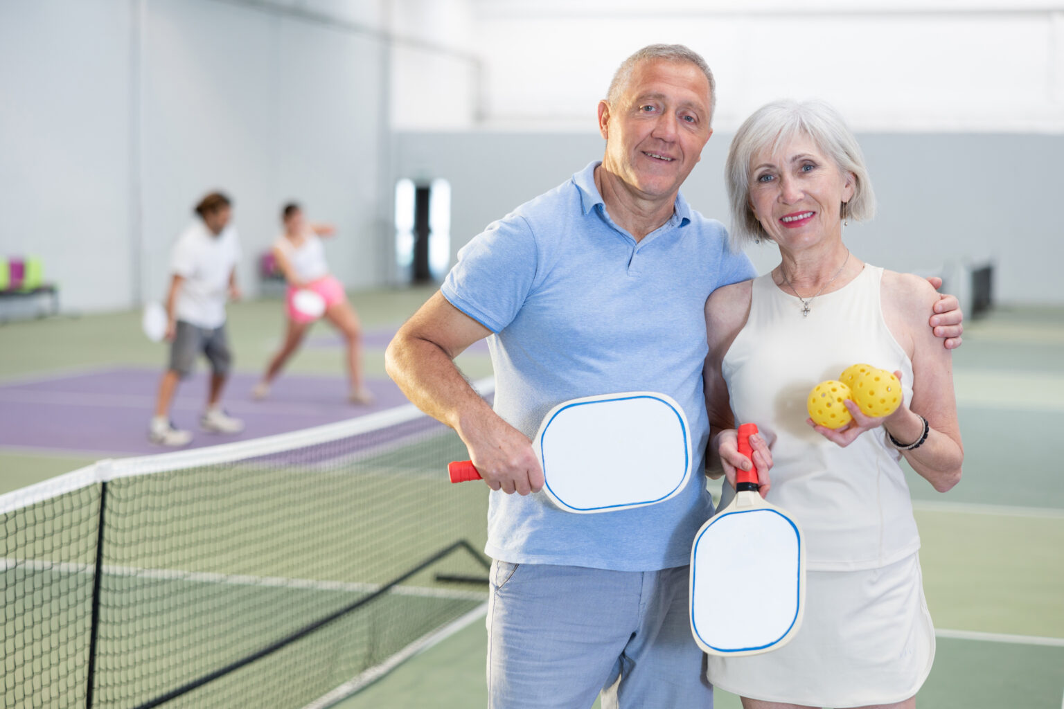 Portrait of a positive elderly couple after playing pickleball with rackets in their hands